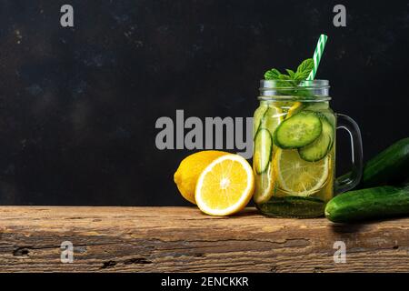 Detox water with sliced lemon and cucumber in a jar on dark background. Healthy concept. Stock Photo