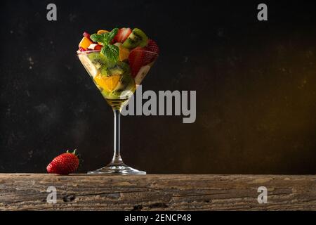 Fruit cocktail in martini glass on wooden table. Food vegan concept. Stock Photo