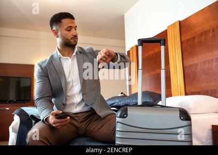 Businessman looking on his watch while sitting down Stock Photo