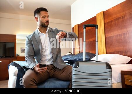 Businessman looking on his watch while sitting down Stock Photo