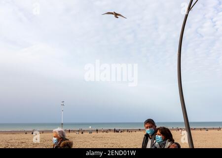 While the first weekend of sunshine and good weather settles in after several days of negative temperatures in the country, and the measures of containment and fight against covid are still effective, tourists flock to the small seaside town on the border with France. Holidaymakers go to the beach and pass an empty cafe that is closed because of COVID. Stock Photo