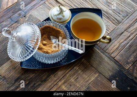 Cup of tea with a pot of brown sugar on a wooden table Stock Photo