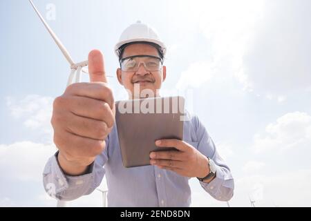 Engineer windmills are working on tablet PC with the wind turbine in background Stock Photo
