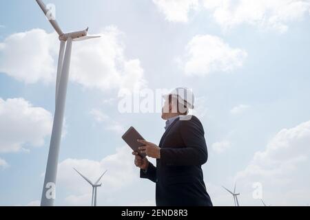 Engineer windmills are working on tablet PC with the wind turbine in background Stock Photo