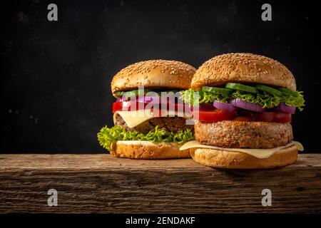 Two fresh tasty burgers on wooden rustic table. Food background. Stock Photo