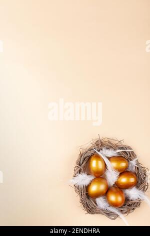 Empty space for text, a banner of happy Easter. Painted golden eggs, white feathers. copy space flat lay top view Vertical nest with eggs Stock Photo