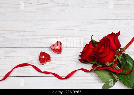 Heart shaped candles and red roses on white wooden background. Valentine’s day and holiday romantic flat lay top view image Stock Photo