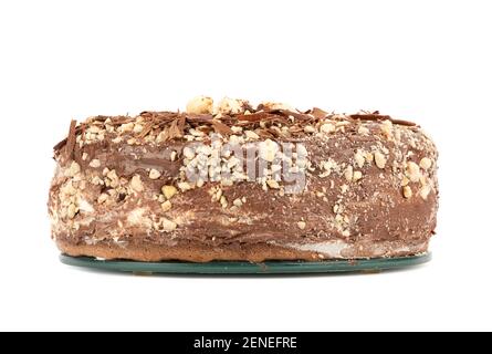 Sponge cake sprinkled with chocolate chips and hazelnuts. Cake on a glass stand over a white background. Homemade cake. Stock Photo