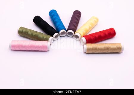 photography of sewing threads of different colors on white background Stock Photo