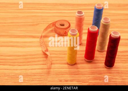 photography of sewing threads of various colors and sewing tools on light wooden background Stock Photo