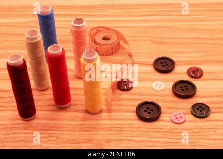 Photograph of multi-colored sewing threads and sewing tools on light wooden background Stock Photo