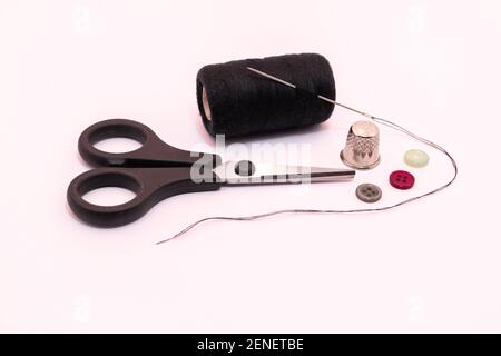Photograph of sewing threads, needles, scissors and buttons on white background. Stock Photo