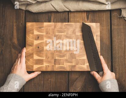 empty rectangular wooden board and female hands with a knife, top view Stock Photo
