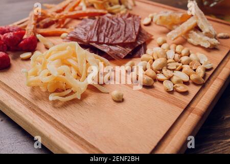 Wine and snack set. Variety of cheese, olives, prosciutto, roasted baguette slices, grapes on wooden board and glasses of red wine over grey marble ba Stock Photo