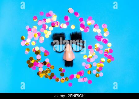 funny face - fake eyeglasses, nose and mustache, confetti, sequins on blue background Happy fools day concept 1st April party Holiday card Stock Photo