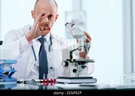 scientist studying vaccine samples through a microscope . Stock Photo