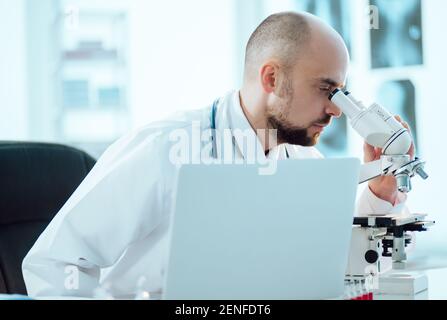 scientist works on a laptop while sitting at a table in a medical laboratory. Stock Photo