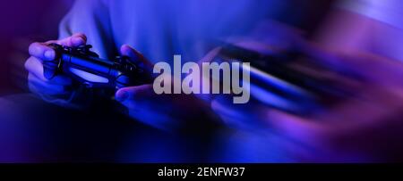 gamers playing console video games. controller in hands closeup. neon lights banner Stock Photo