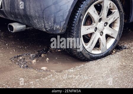 car tire in big pothole on the road Stock Photo