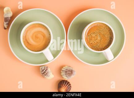 Two cups of aromatic espresso coffee with froth. Traditionony is an Italian breakfast drink with shell-shaped chocolates. Top view.  Stock Photo