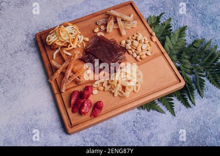 Wine and snack set. Variety of cheese, olives, prosciutto, roasted baguette slices, grapes on wooden board and glasses of red wine over grey marble ba Stock Photo