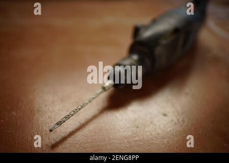Dirty drill lies on a brown floor indoor Stock Photo
