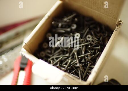 A bunch of new black self-tapping screws in a box. Stock Photo