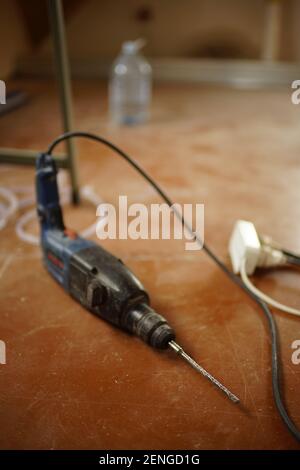 The drill lies on the dusty brown floor of the room Stock Photo