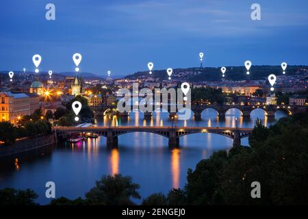 Map pin icons on Prague cityscape. Lit buildings and bridges over Vltava River in Prague, Czech Republic, at dusk. Stock Photo