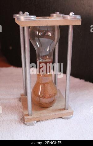 fragile hourglass with red sand inside on metal stand  for present Stock Photo