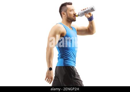 Muscular young man in sportswear walking and drinking a sports energy drink isolated on white background Stock Photo