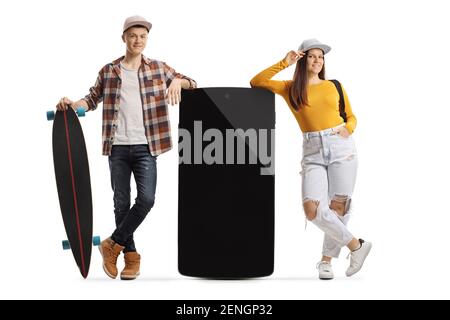 Young male with a longboard and female leaning on a big mobile phone isolated on white background Stock Photo