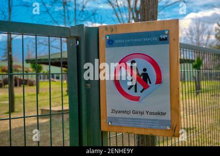 Bursa. Turkey. 09.02.2021. Forbidden sign hanging on zoo park and it says no entrance. Sing board hanging on green fences made of metal. Stock Photo