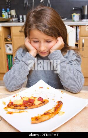 Kind vor Teller mit Pizzaresten, MR: Yes Stock Photo