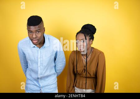Young african american couple standing over yellow background afraid and shocked with surprise and amazed expression, fear and excited face. Stock Photo