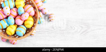 Happy Easter wooden background with pink, yellow and blue eggs. Gift card with colorful easter eggs on white wooden table. Stock Photo