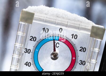 Closeup photo of an outdoor window thermometer covering with snow with negative temperature in degrees Celsius Stock Photo