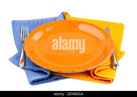 Orange empty plate with knife and fork on blue and yellow  cotton towels isolated on white background. Stock Photo