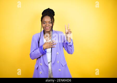 Young african american business woman smiling swearing with hand on chest and fingers up, making a loyalty promise oath Stock Photo