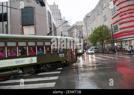 Passengers huddle under colorful umbrellas as they board the iconic New Orleans streetcar on a rainy day on bustling Canal Street. Stock Photo