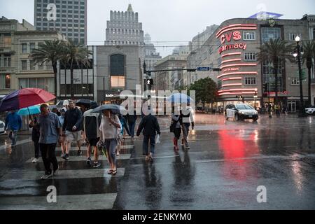 Passengers huddle under colorful umbrellas as they board the iconic New Orleans streetcar on a rainy day on bustling Canal Street. Stock Photo