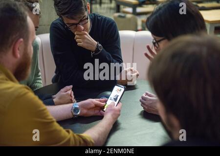Students sitting together, looking at smart phone Stock Photo