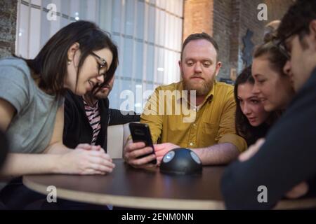 Students looking at smart phone together Stock Photo