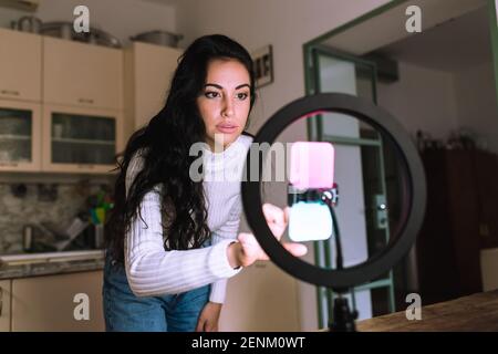 Young woman using mobile phone with ring light Stock Photo