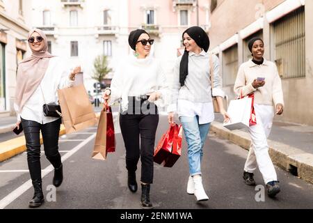 Four female friends walking along street with