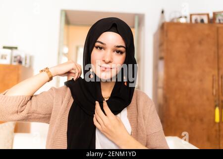 Young muslim woman putting on hijab headscarf Stock Photo