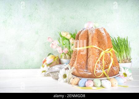 Easter sweets and decorations background, Sweet easter cake panettone with colorful painted eggs, spring grass and decor, copy space for text Stock Photo