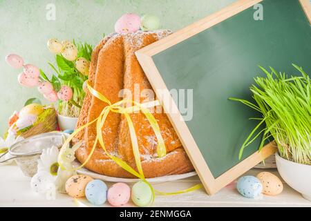 Easter sweets and decorations background, Sweet easter cake panettone with colorful painted eggs, spring grass and decor, copy space for text Stock Photo