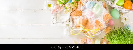 Easter sweets and decorations background, Sweet easter cake panettone with colorful painted eggs, spring grass and decor, copy space for text Stock Photo