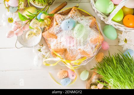 Easter sweets and decorations background, Sweet easter cake panettone with colorful painted eggs, spring grass and decor, copy space for text Stock Photo